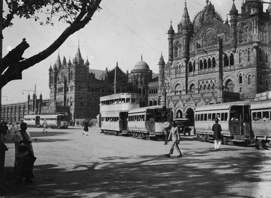 Intorno al 1915: i tram passano davanti alla grande facciata della stazione ferroviaria di Victoria a Bombay (ora Mumbai).